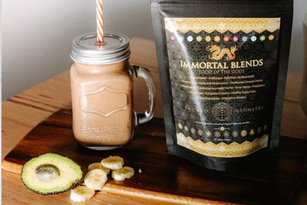 Packet of Food of the Gods Superfood on a table with a smoothie with banana and avocado.