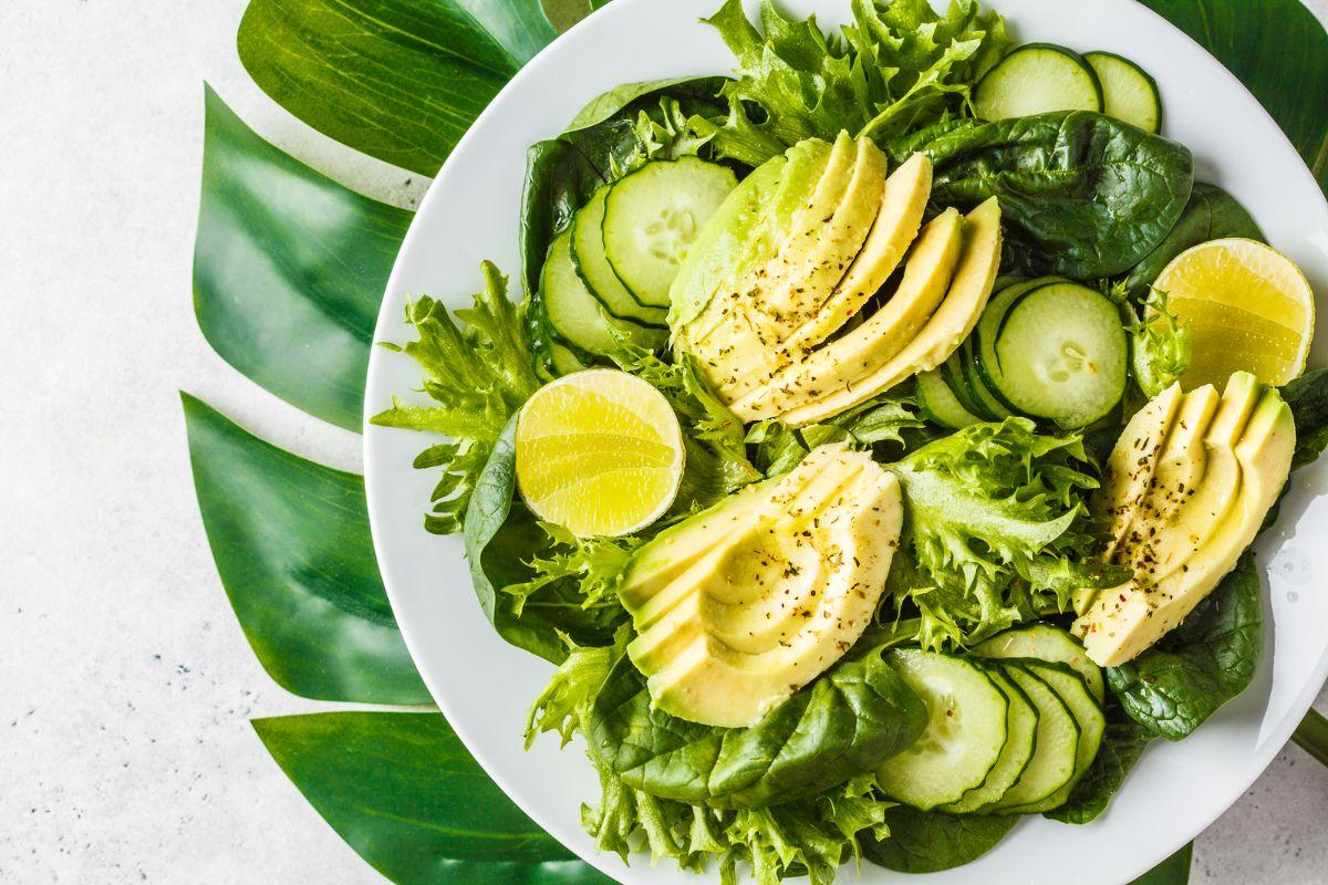 Plant-based food in a bowl; avocado, limes, lettuce, cucumber, kale, spinach 
